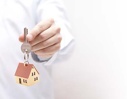 man holding a house key with a keyring of a house on it